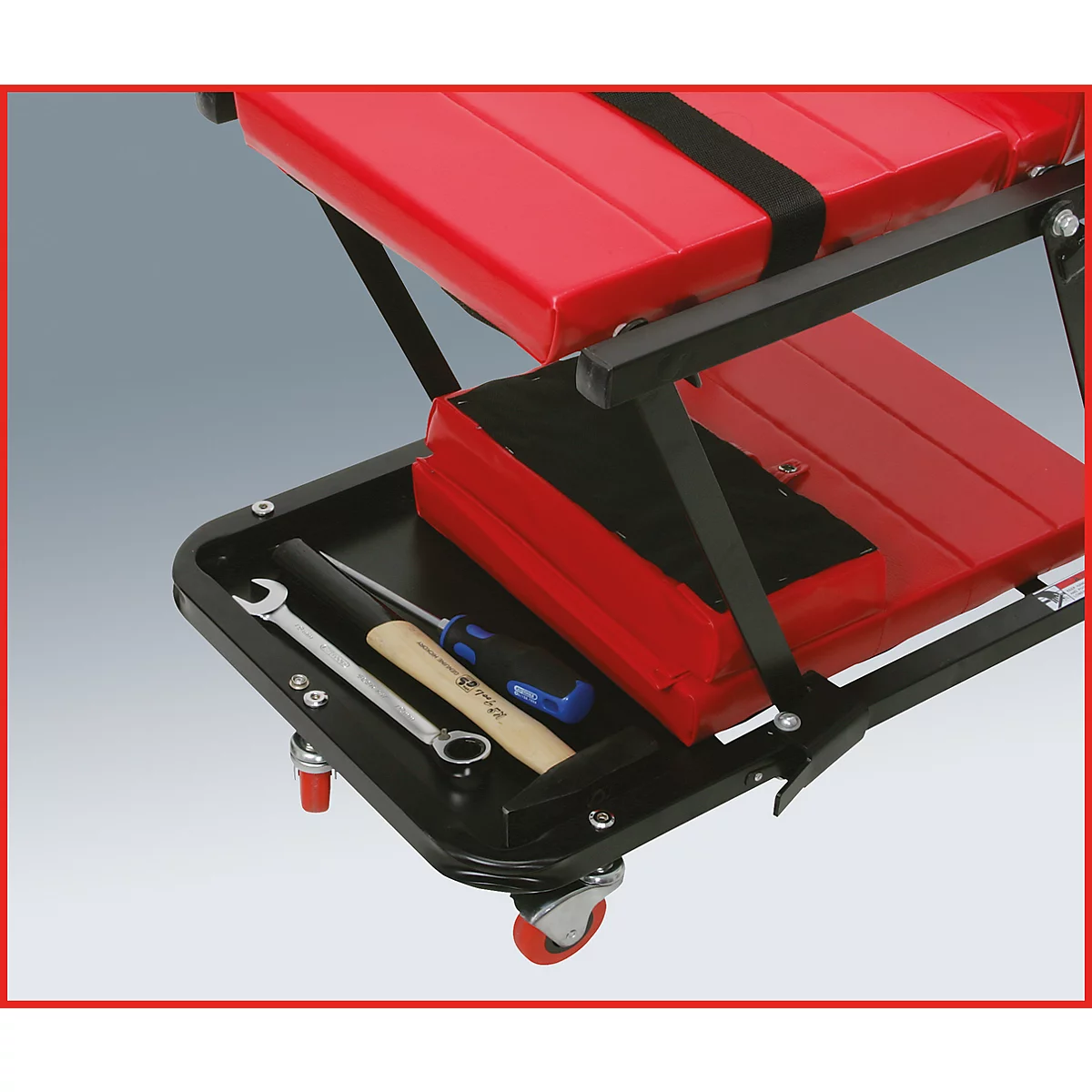 Un chariot à outils avec un siège et une étagère rouges. Des outils dessus, tels que des clés et un marteau.